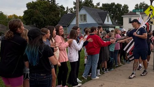 Sixth grade students giving high five to firefighters on their walk
