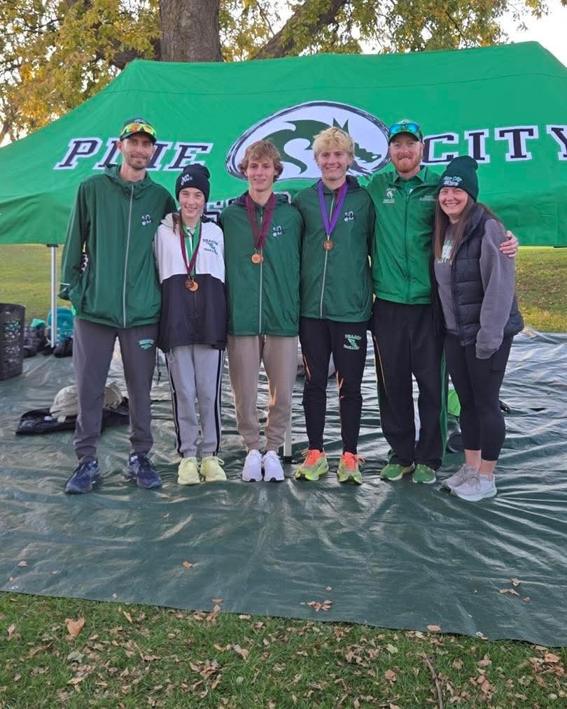 Cross Country athletes and coaches pose in front of Dragon tent with section medal honors as the qualify for the state tournament.