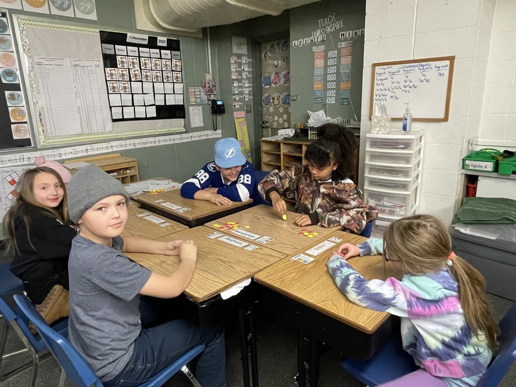 Five elementary students seated at desks playing a game during the holiday season.