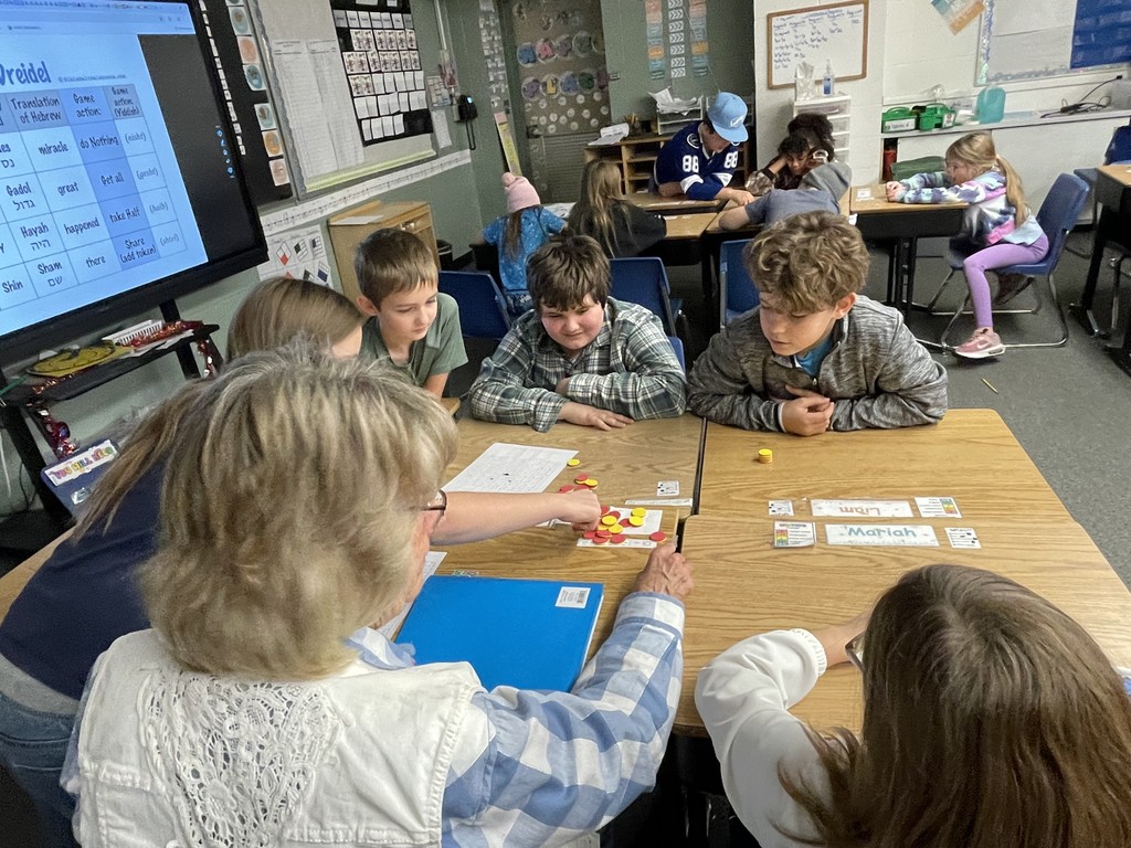 Five elementary students work with a para to learn a new game during the holiday season.
