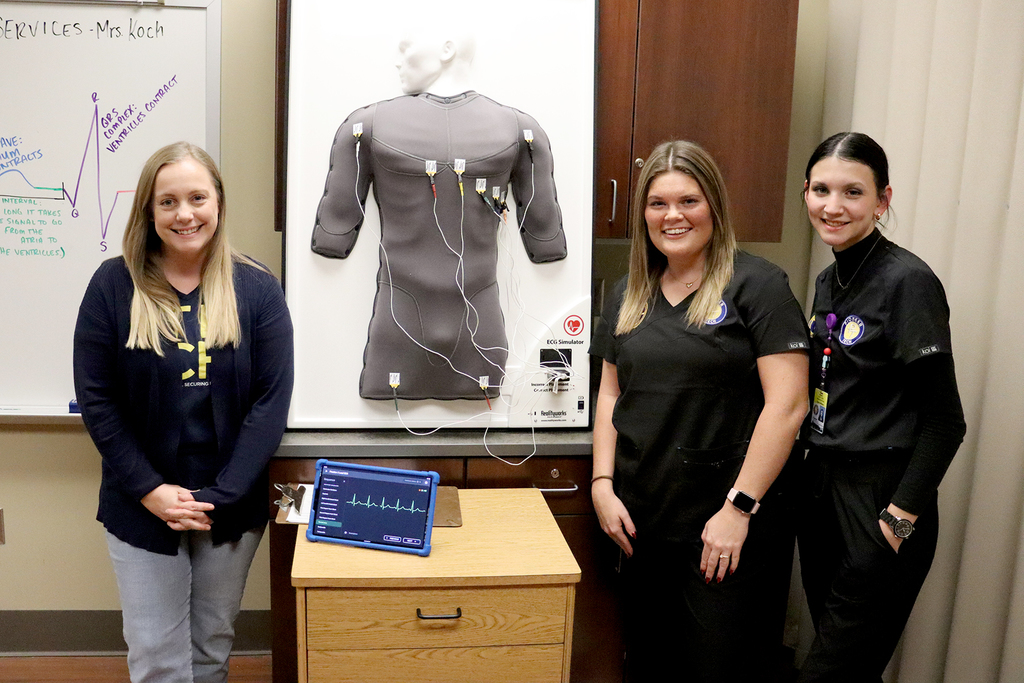 Pioneer Tech students next to training item in Medical Services 