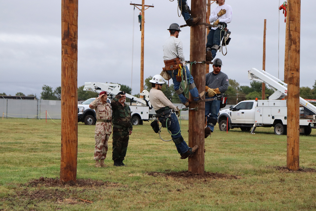 Pioneer Tech men on poles with one saluting. 