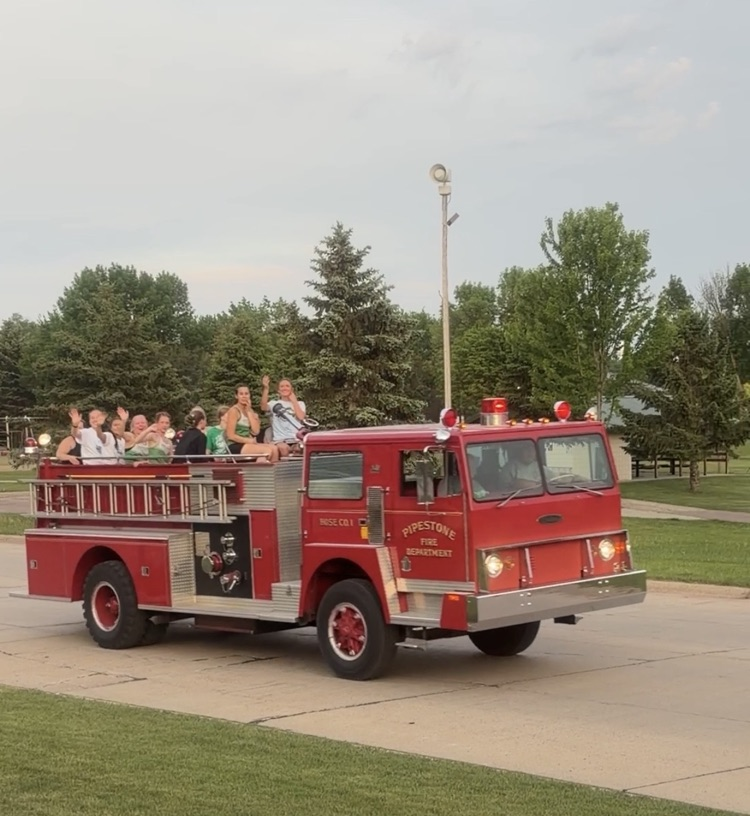Track athletes riding on a fire truck celebrating an athlete heading to the state track tournament