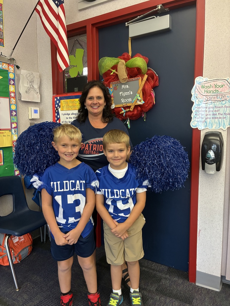 Mrs. Flynn and two wildcat football players in her first grade classroom. 
