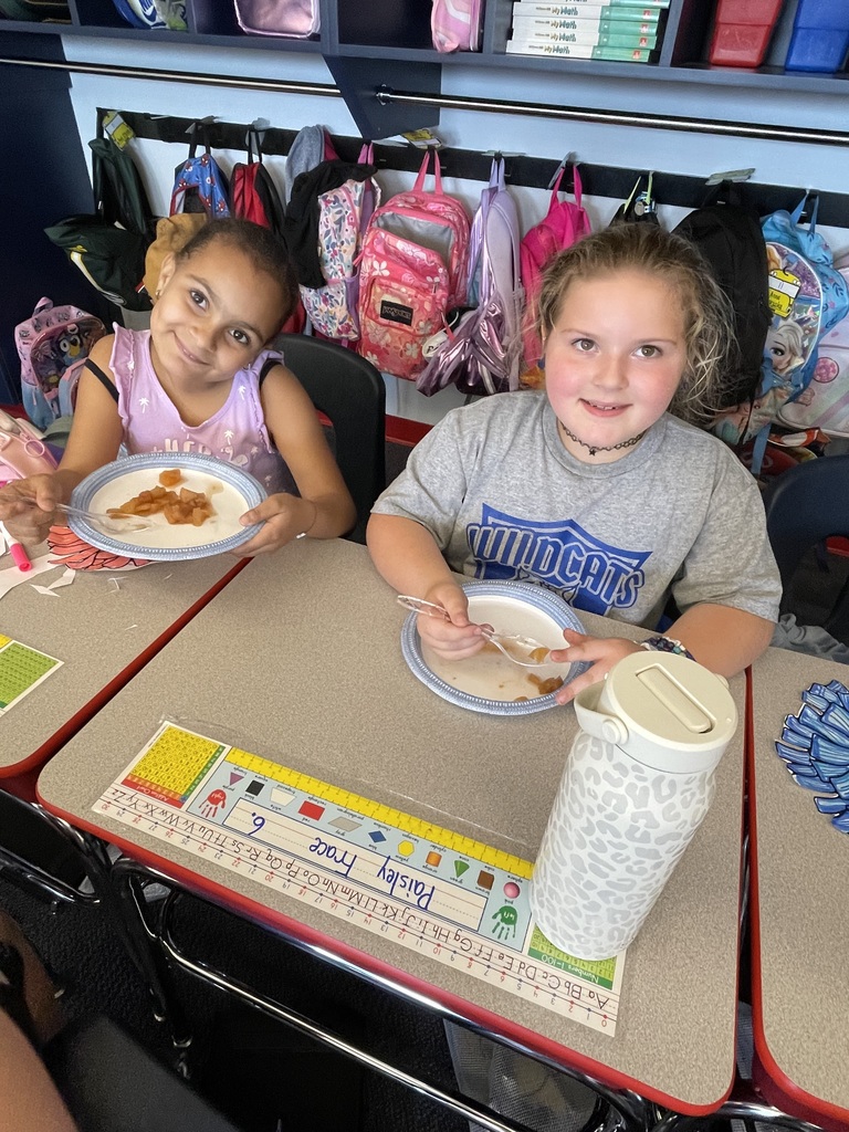 Two girls eating applesauce smiling