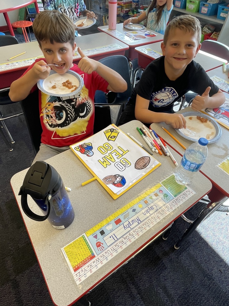 Two boys eating apple sauce giving thumbs up