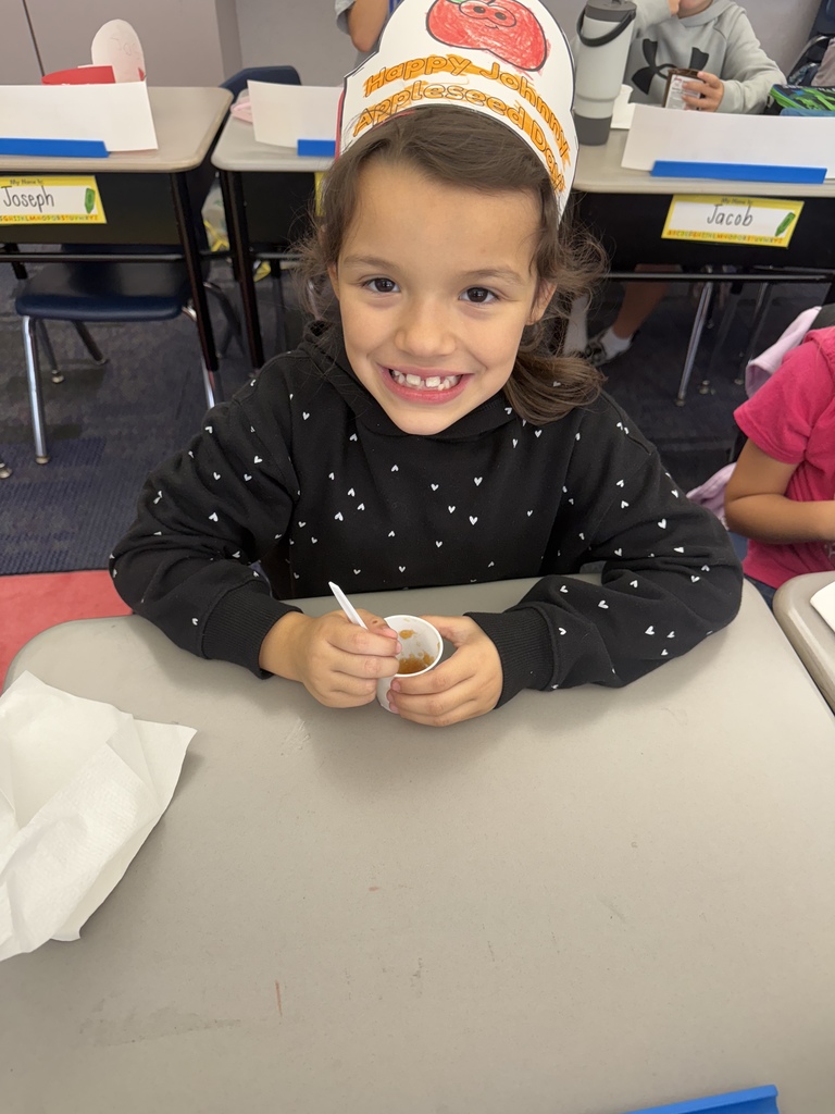 A student smiling eating homemade applesauce. 