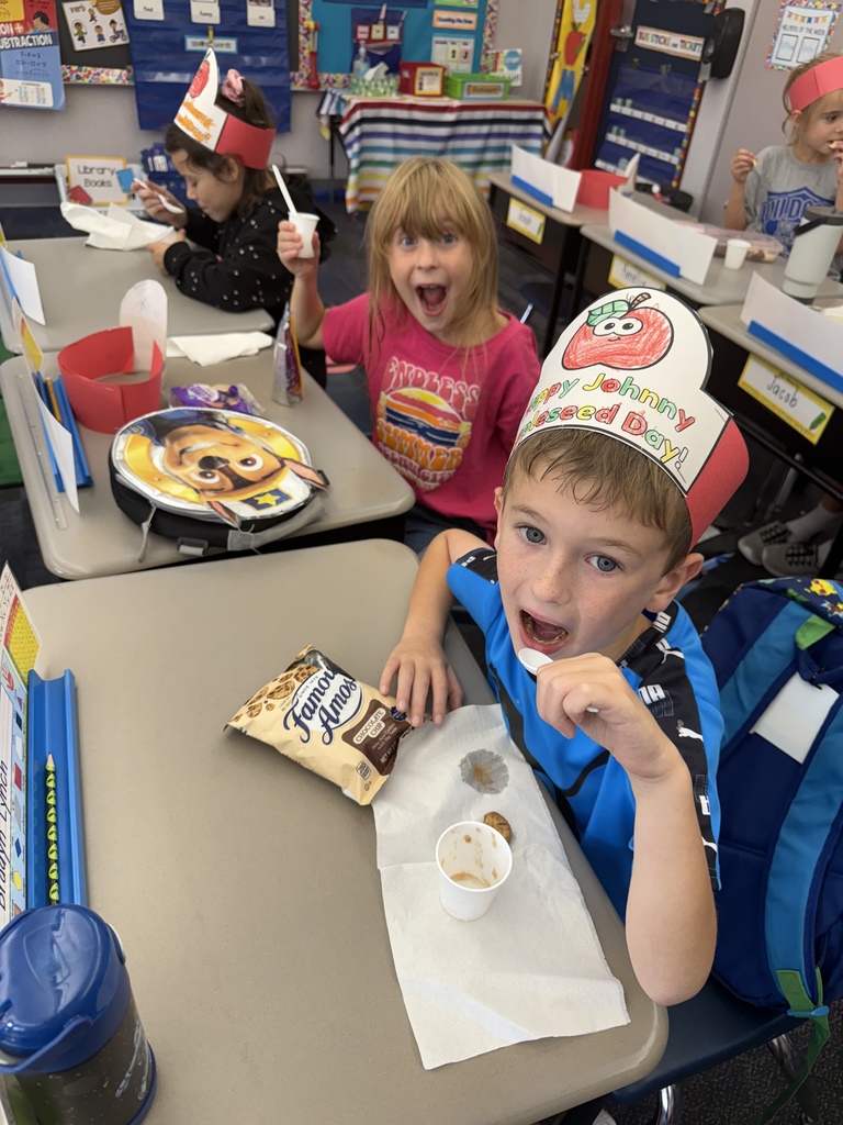 Students seated eating snack including spoonfuls of homemade apple sauce. 