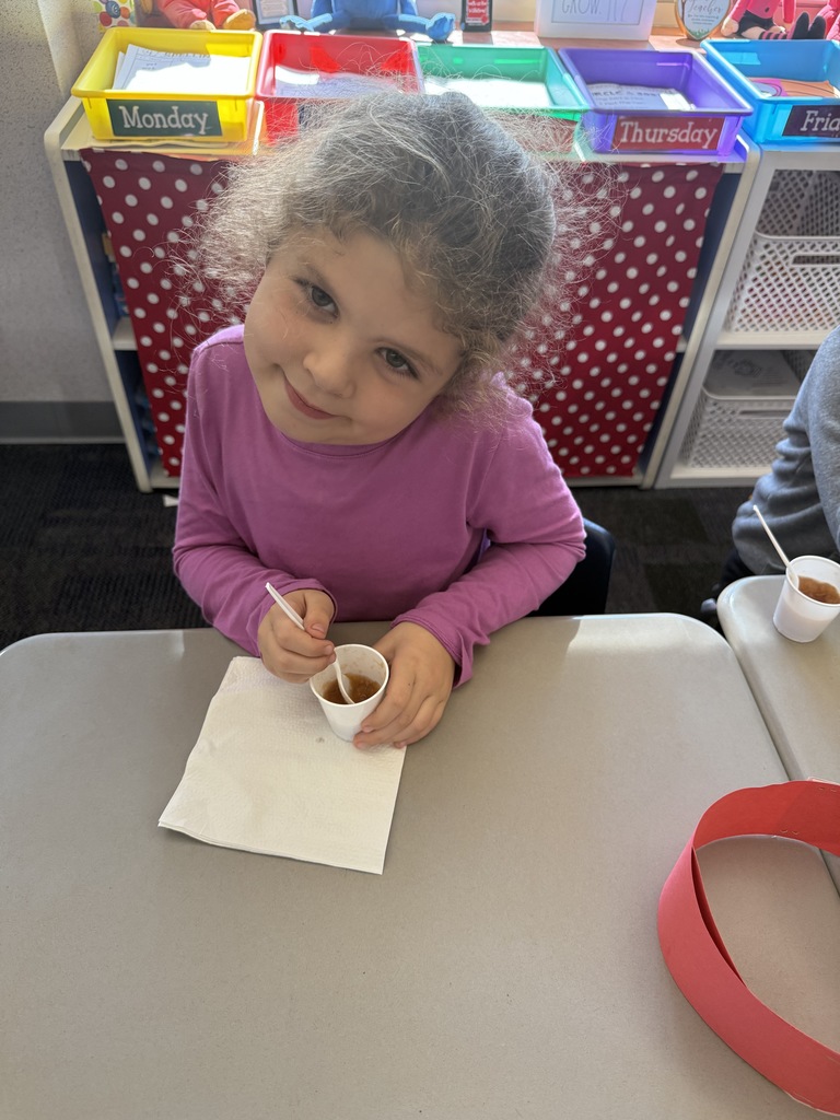 A student smiling eating homemade applesauce. 