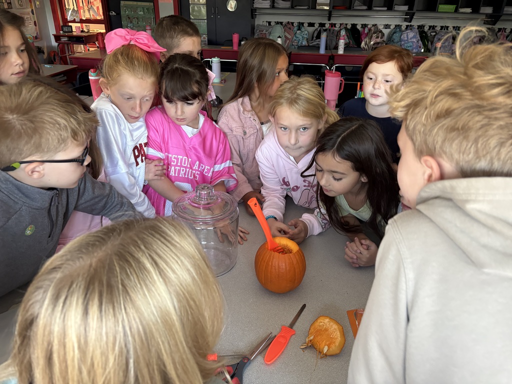 A group of students looking inside a carved pumpkin
