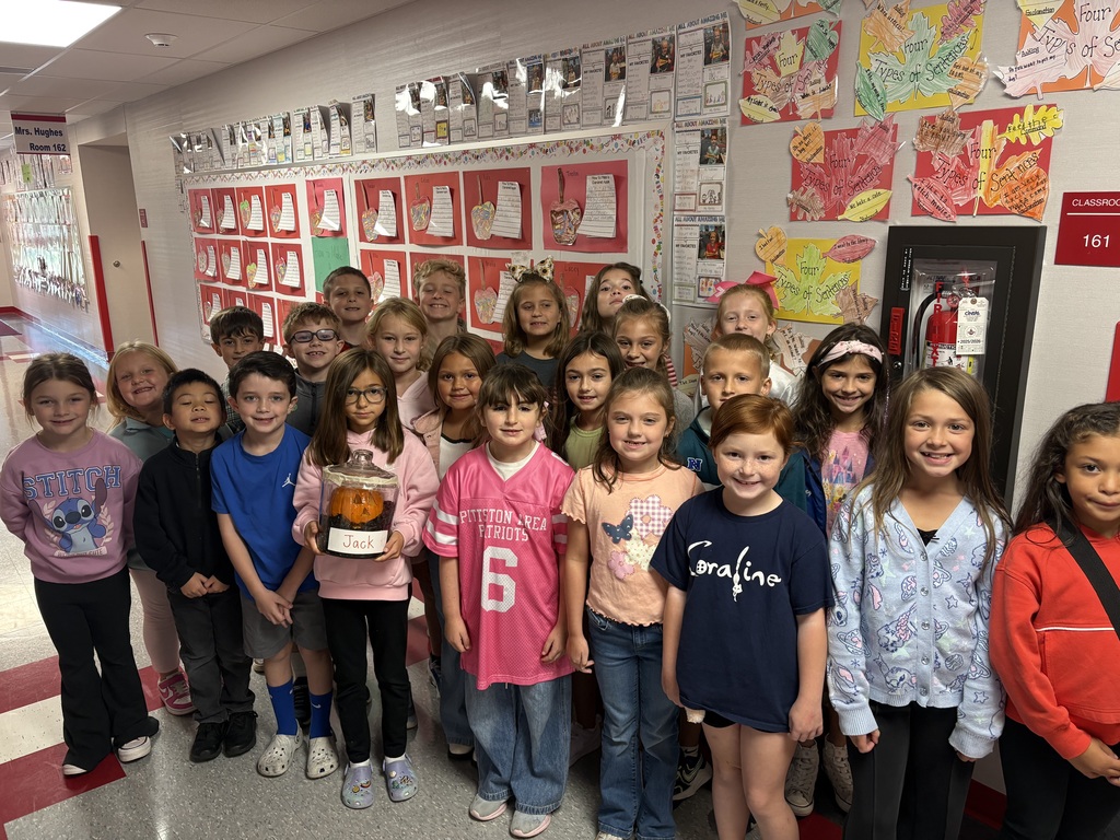 A group of students holding a pumpkin in a glass jar labeled jack