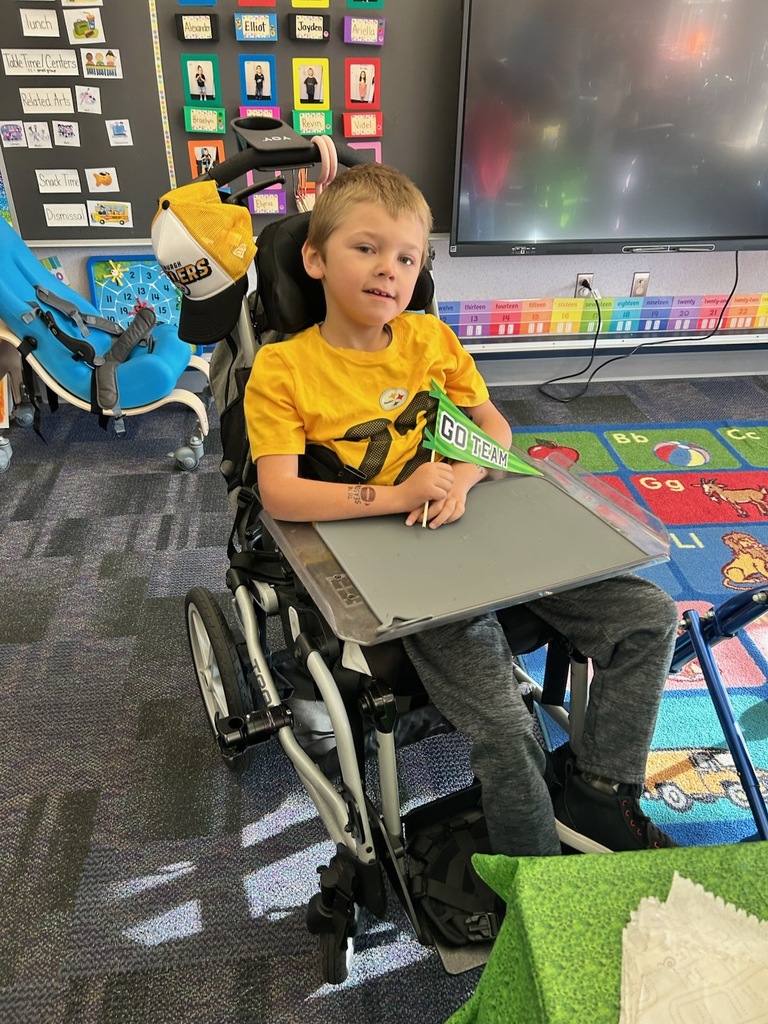 A boy sitting holding a go team pennant.