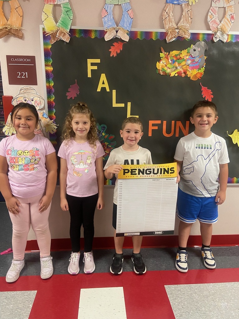 Four students holding a penguins reading long poster