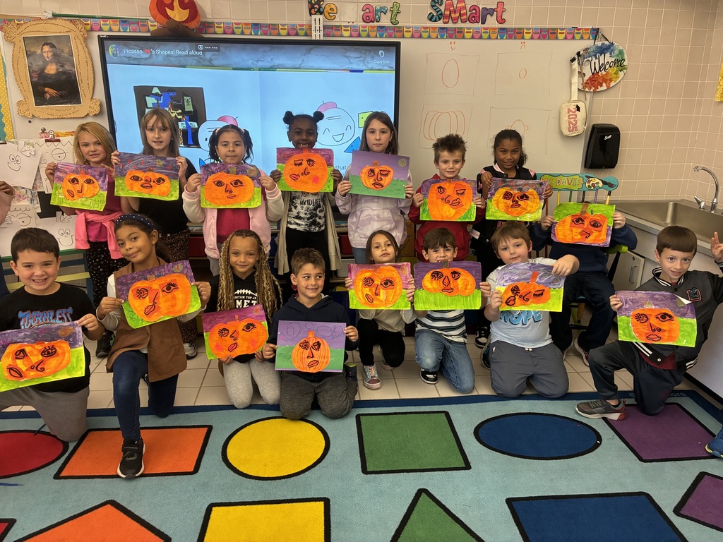 A group of students holding picasso inspired pumpkin paintings.