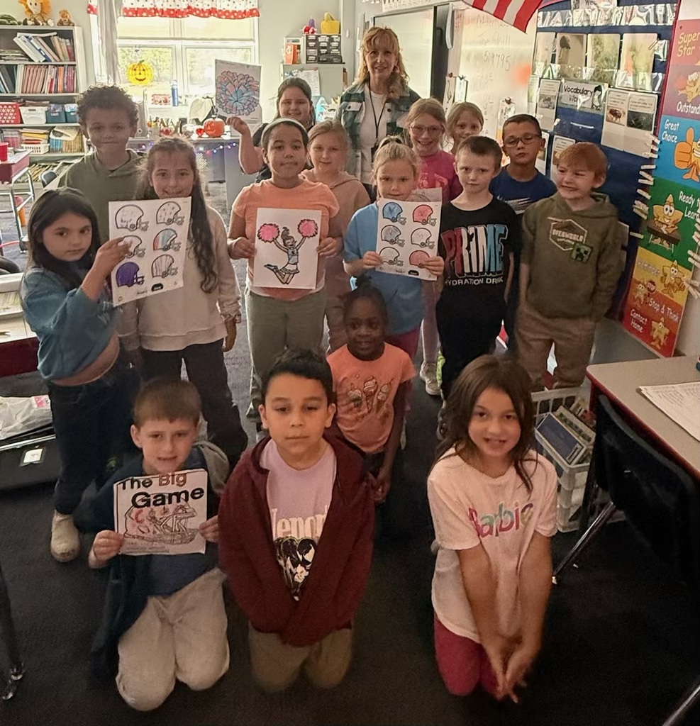 Students in a classroom holding red white and blue coloring pages with footballs and cheerleaders.