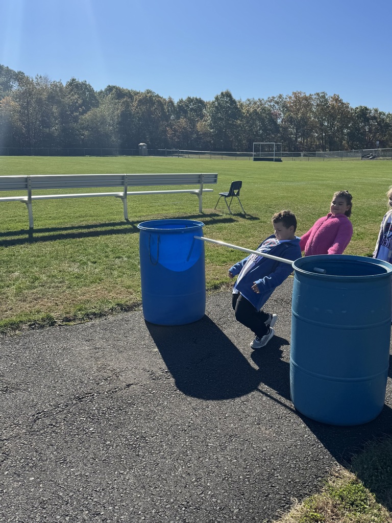 A boy doing the limbo between two blue garbage cans.