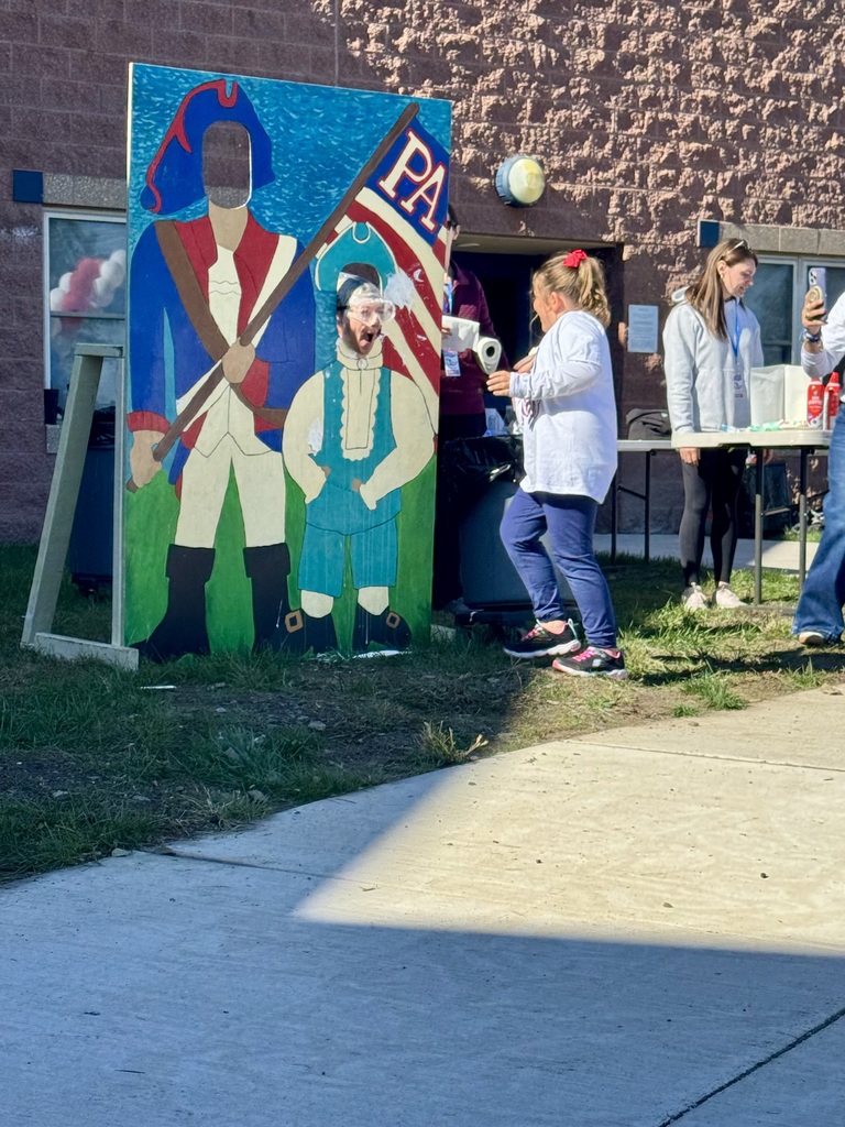 A girl throwing a pie at a teacher in a patriot cut out.