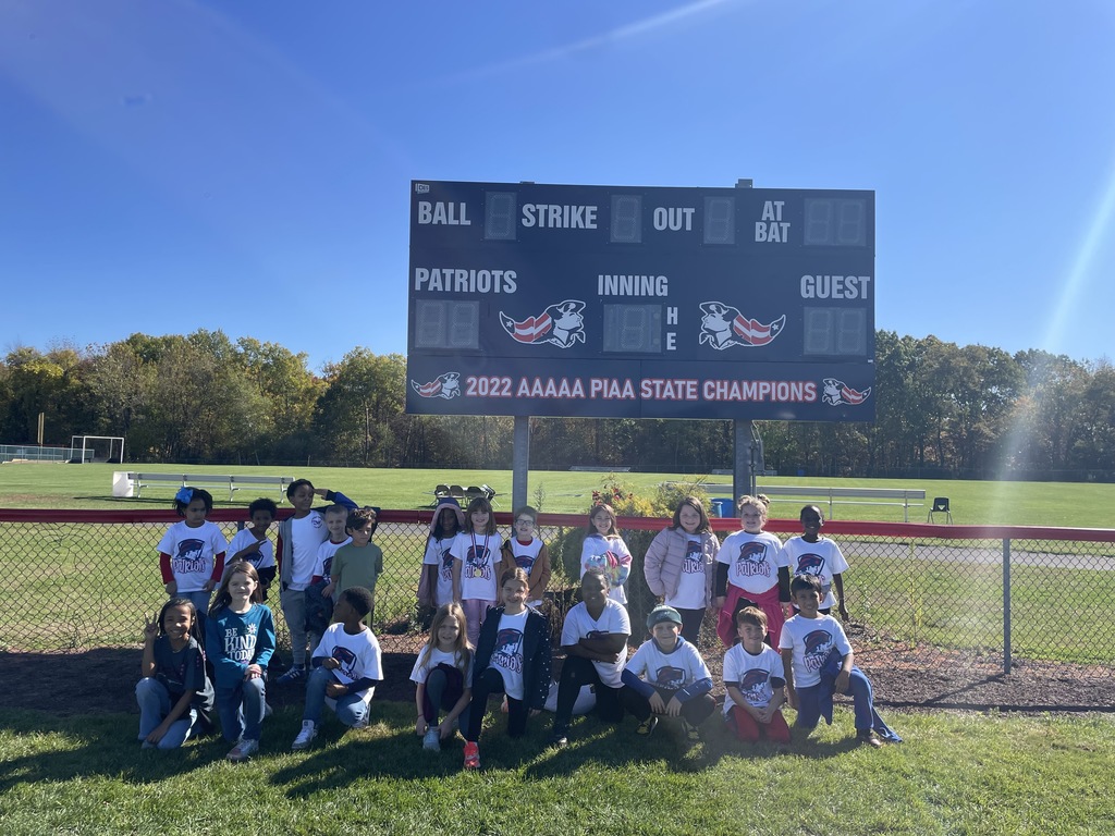 A group of students smiling at the camera under a sign.