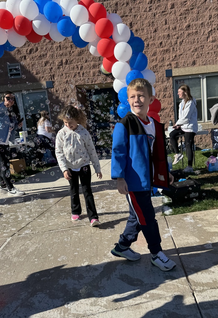 A student smiling under a balloon arch.