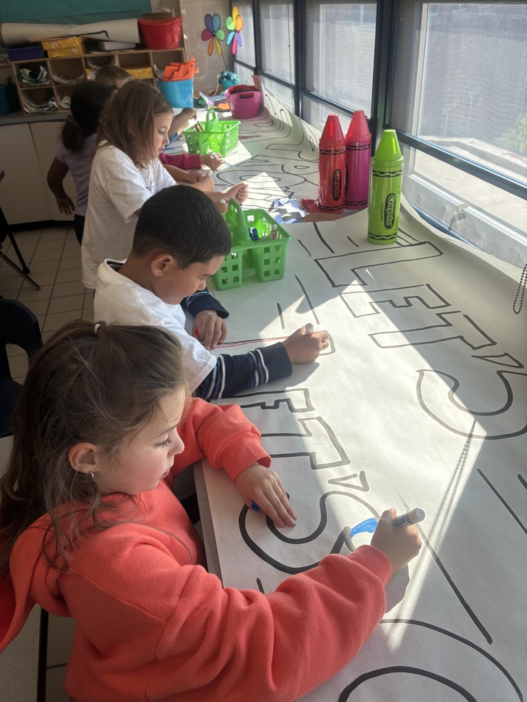 Students coloring a banner with red and blue markers.
