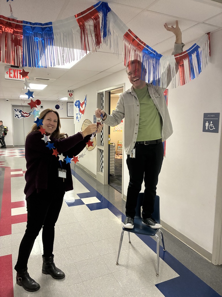 Teachers decorating a hallway with red and blue decorations.