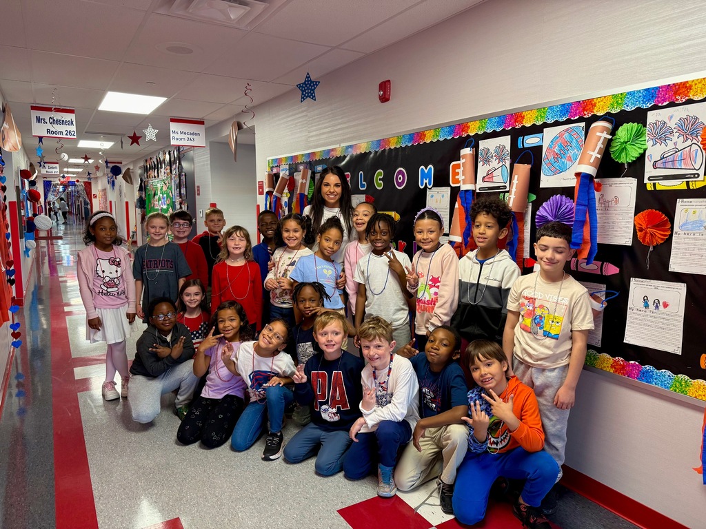 A group of students with their teacher in a hallway posing for a group photo.