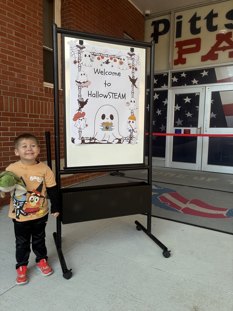 A boy smiling in front of a welcome to hallosteam sign.
