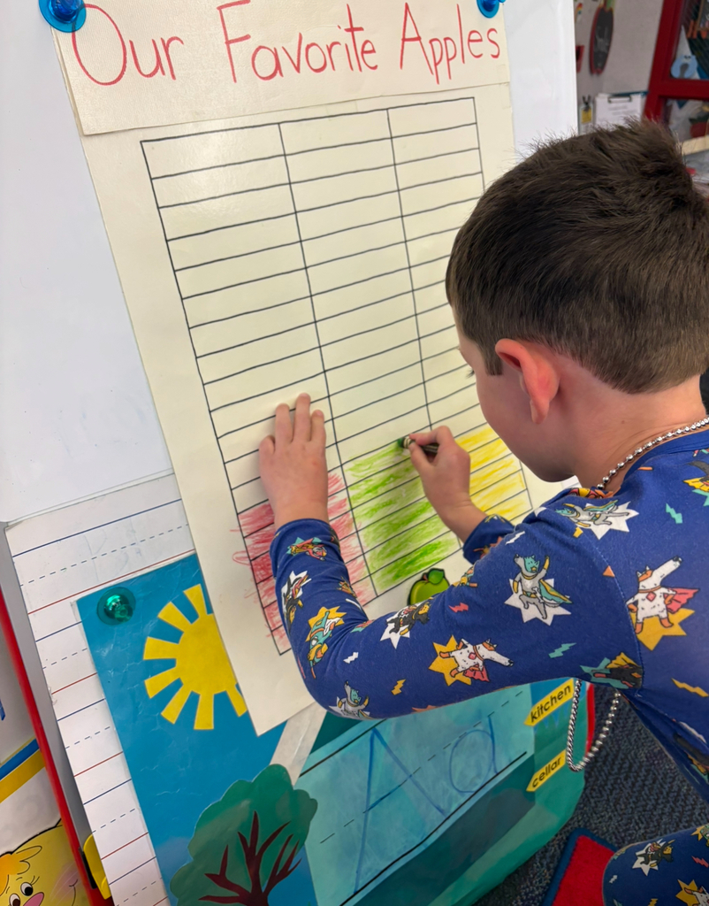 A boy coloring green on a bar graph.