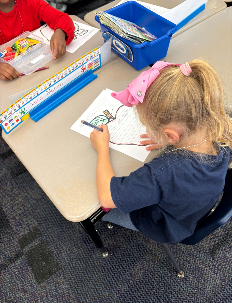 A girl writing about apples.