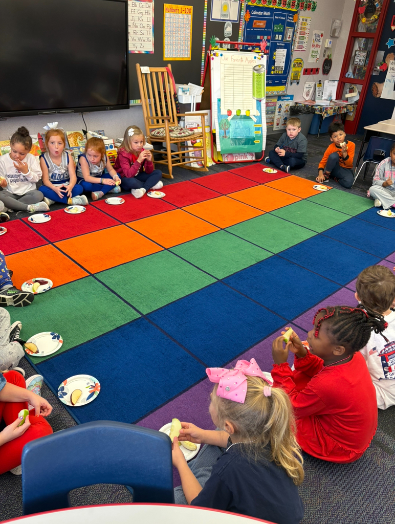 Students sitting around a carpet tasting apples.