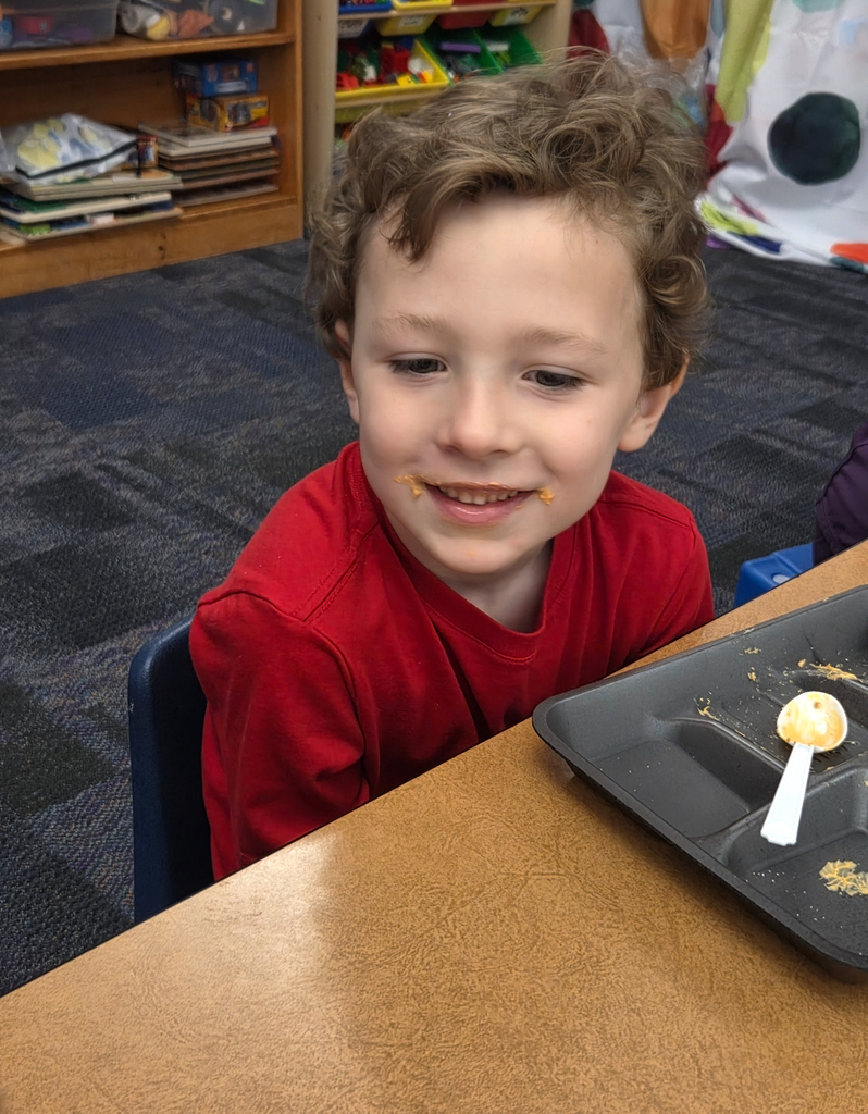A student holding a square graham cracker decorated like an orange pumpkin.