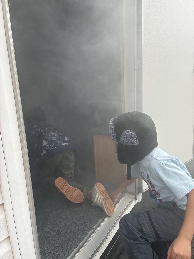 Students in a smoke house filled with smoke.