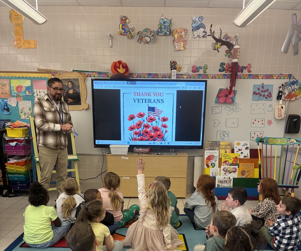 A group of kids in art class on the carpet learning about poppies.