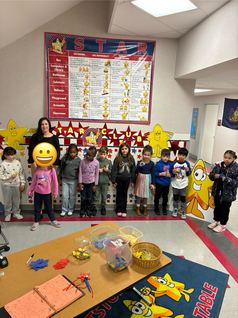 A group of students standing in-front of the star board in a school hallway,