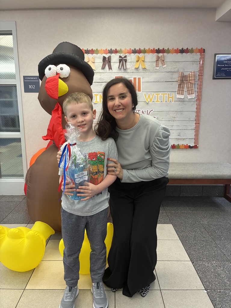 Elliot Moran and Tiffany Ferentino posing infront of a turkey inflatable. Elliot is holding a red and blue prize.