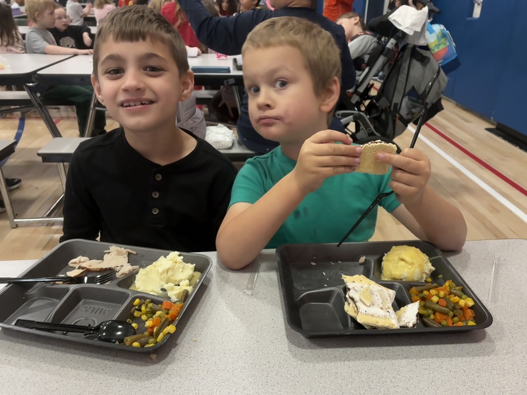 Kids eating a thanksgiving meal in a cafeteria.