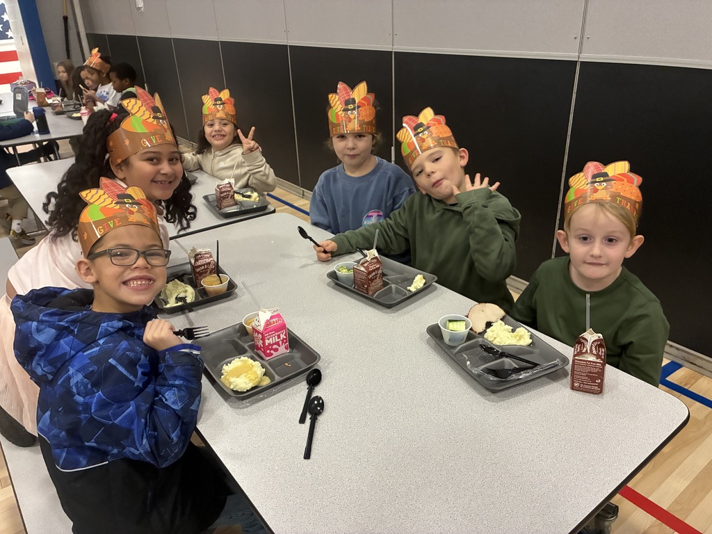 Kids eating a thanksgiving meal in a cafeteria.