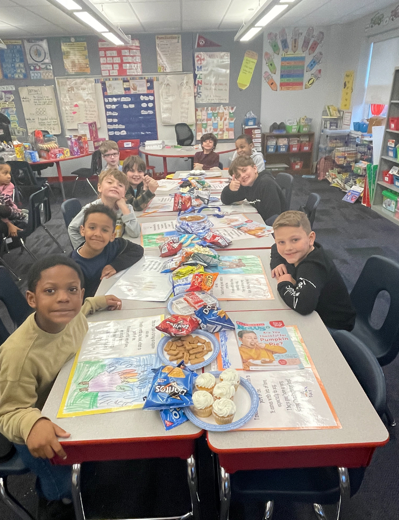 A class of second grade students seated in their classroom eating thanksgiving foods