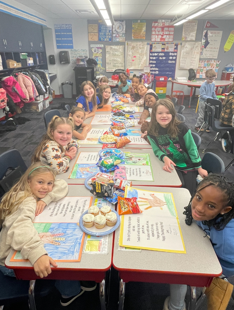 A class of second grade students seated in their classroom eating thanksgiving foods