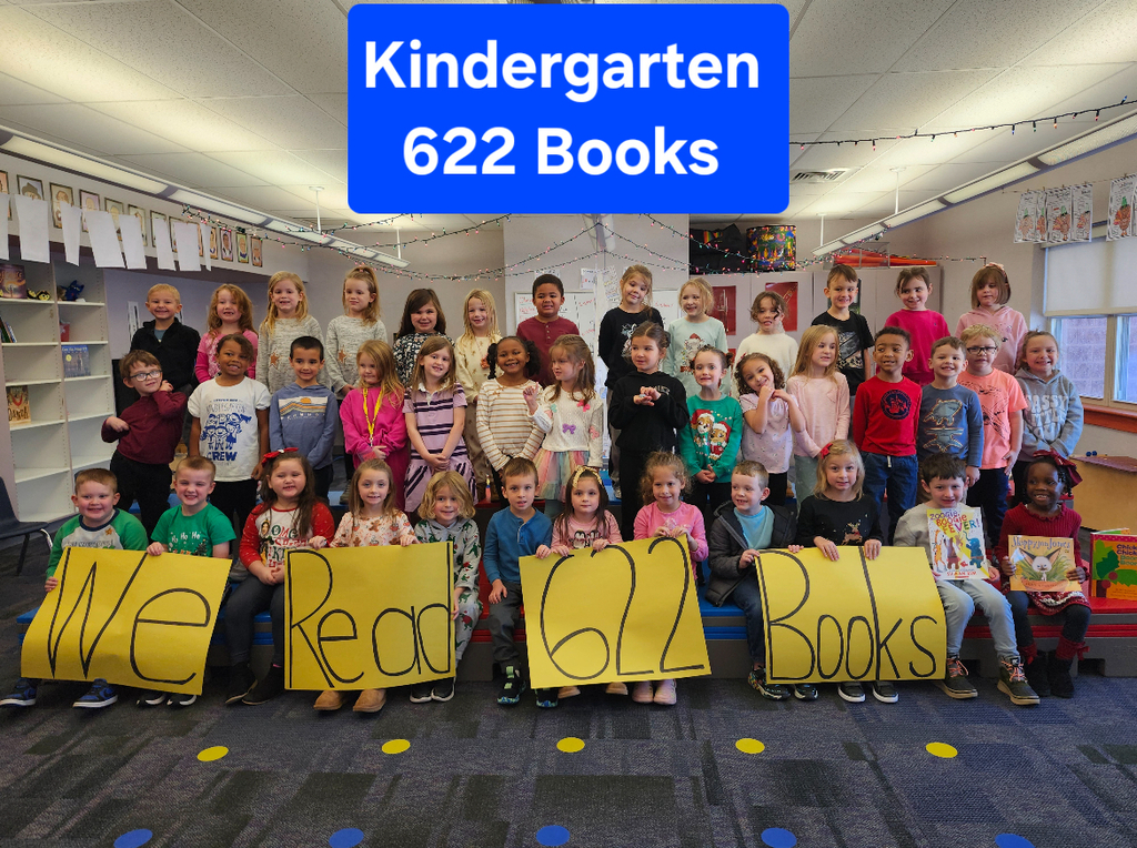Students in a group smiling at teh camera holding yellow signs with the words we read books.
