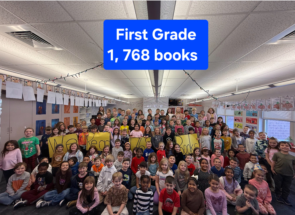 Students in a group smiling at teh camera holding yellow signs with the words we read books.