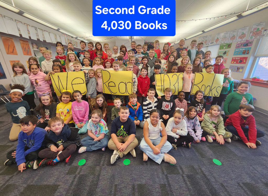 Students in a group smiling at teh camera holding yellow signs with the words we read books.