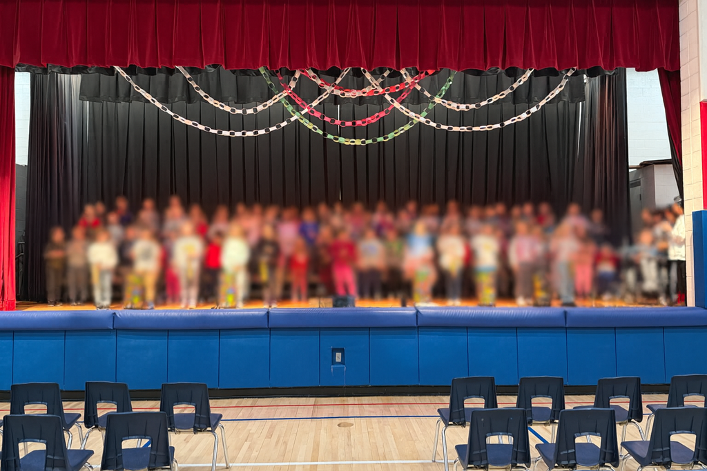 A decorated stage in a gym with students blurred.