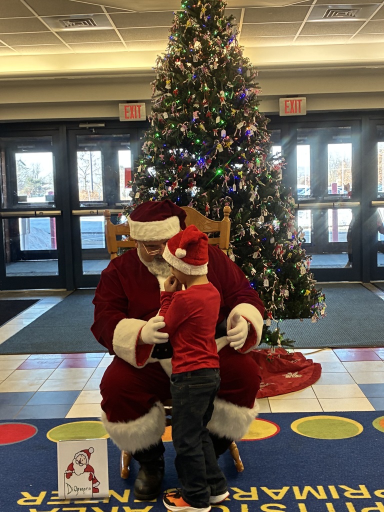 Santa with a student in-front if the christmas tree.
