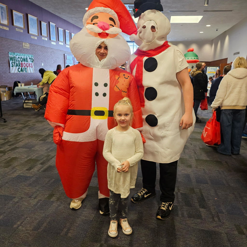 A girl posing with an inflatable santa and snowman 