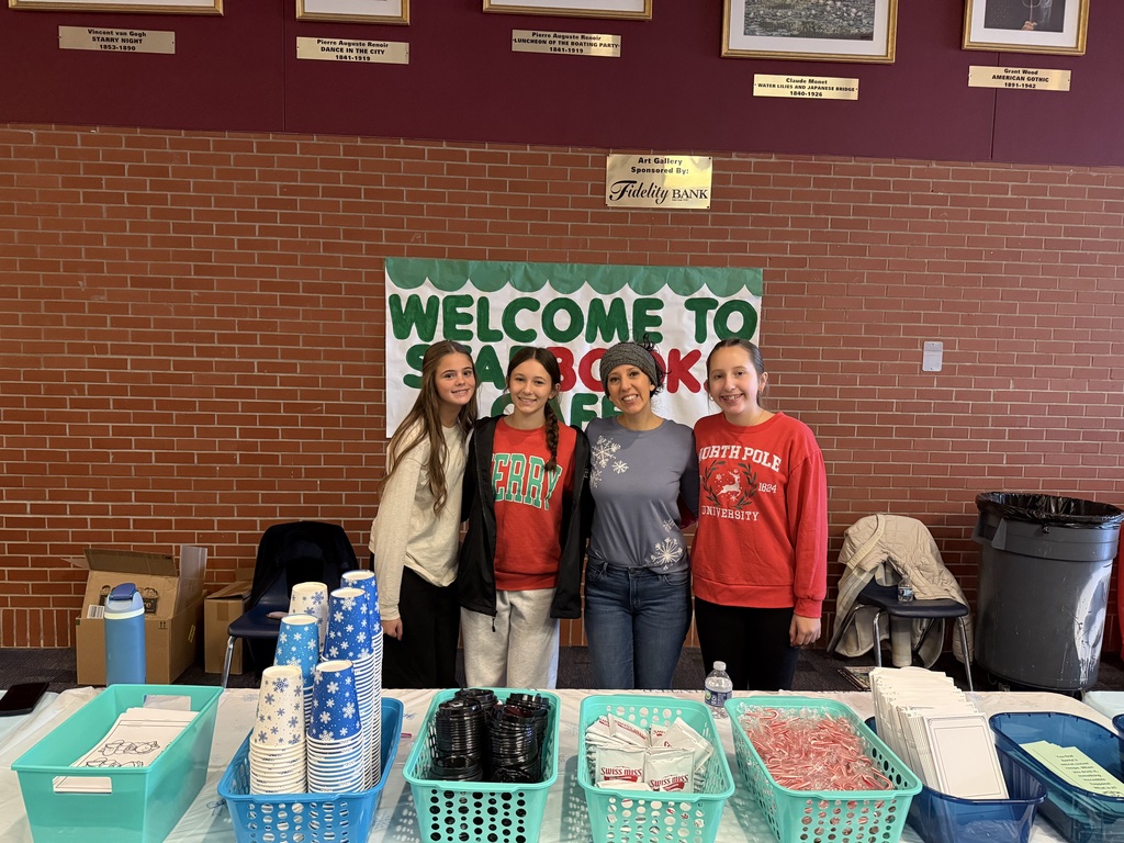 Teachers standing behing a table with hot cocoa supplies. 