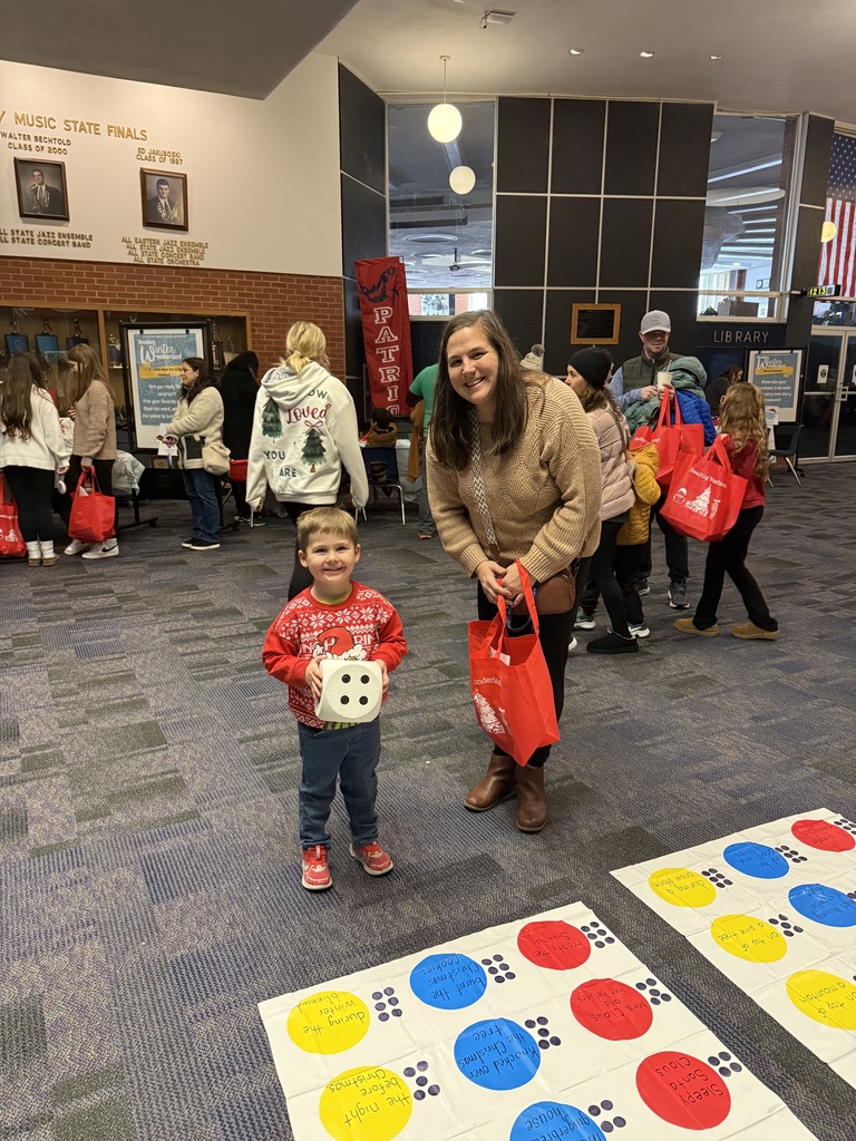 A mom and a boy holding a di infront of a twister board. 