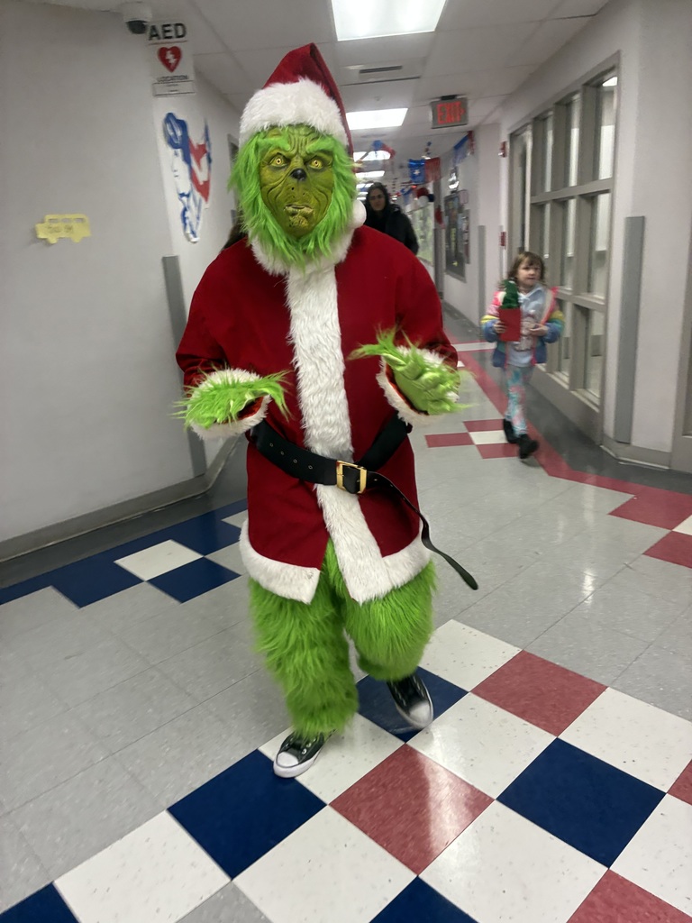 A man in a grinch costume in a school. 