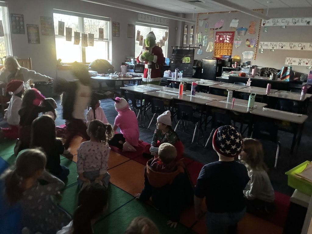 A man in a grinch costume in a school. 
