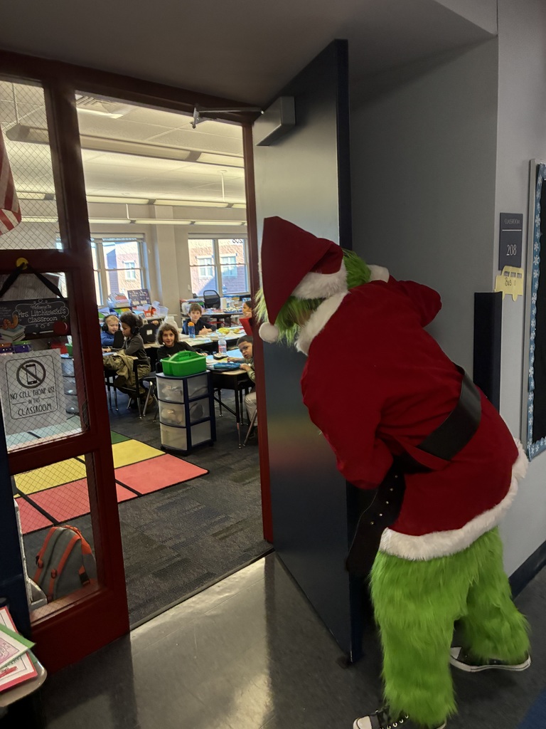 A man in a grinch costume in a school. 